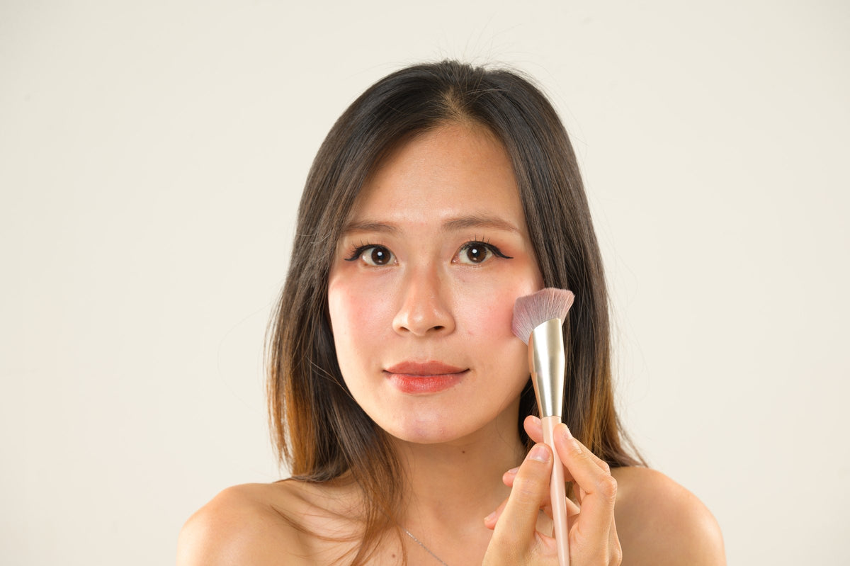 A woman sweeping blush onto her cheekbone with a make-up brush