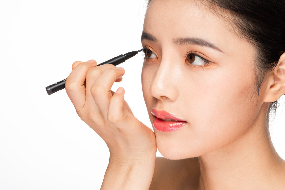 A young woman applying eyeliner