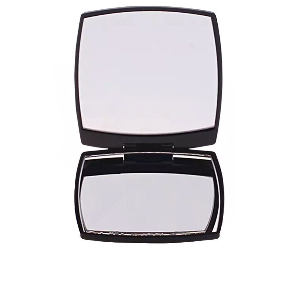 Polished metal compact mirror showing hinge, two reflective faces; Chanel branding subtly engraved on exterior.