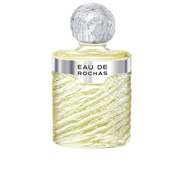 Clear glass bottle of Eau de Rochas with rippled design, citrus and floral scent.
