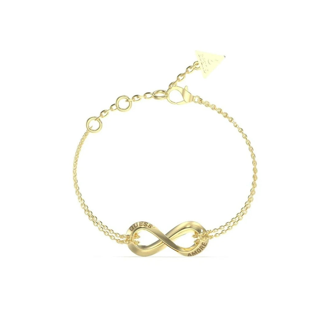 Gold double-chain bracelet featuring an infinity charm, lobster clasp, and small triangle tag on neutral background