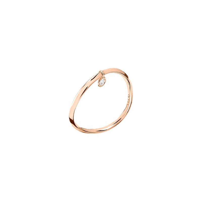 Rose gold bangle with a single dangling clear diamond charm on warm metal background