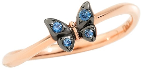 Rose gold butterfly ring with blue gemstones and black metal accents on a neutral surface